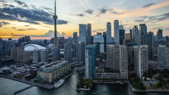 Cityscape view of Toronto from the harbour with the CN Tower and downtown standing against a dramatic sky.